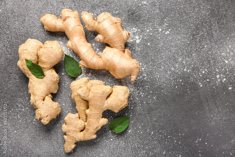 Fresh ginger roots and leaves on grey background