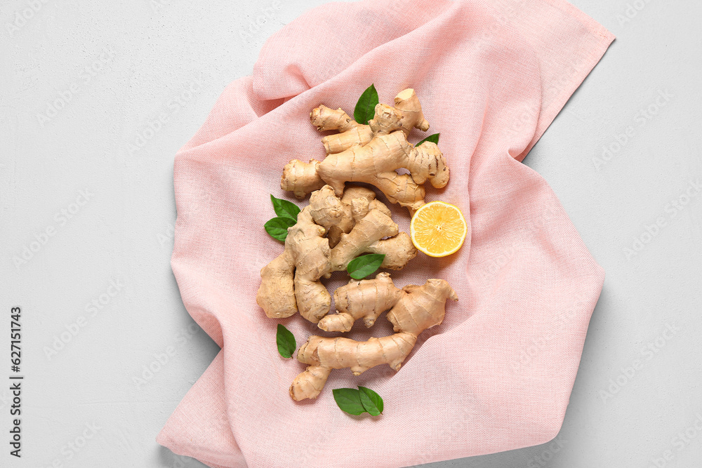 Fresh ginger roots with half of lemon and leaves on white background