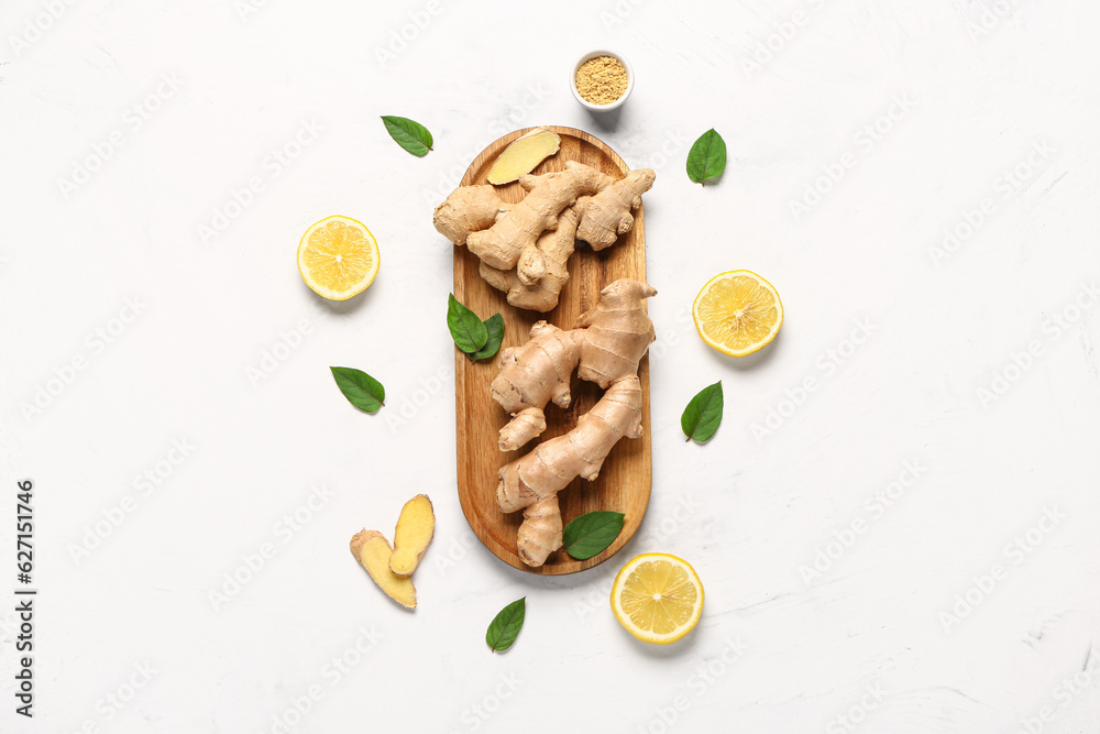 Wooden board with fresh ginger roots and slices of lemon on white background