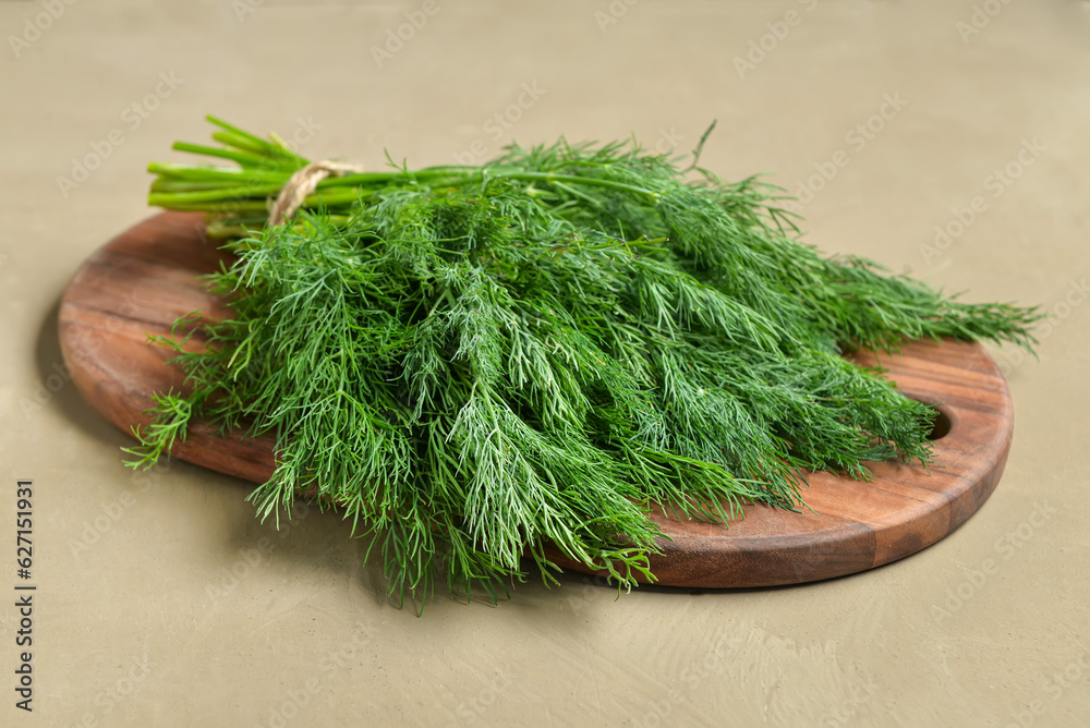 Wooden board with bunch of fresh dill on grey background