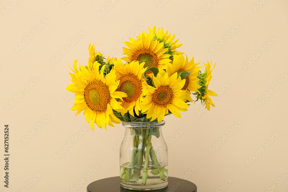 Vase with beautiful sunflowers on table near beige wall in room