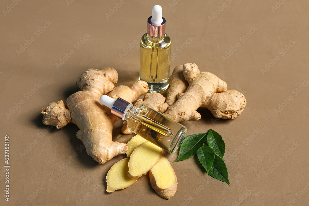 Bottles of ginger cosmetic oil and leaves on brown background