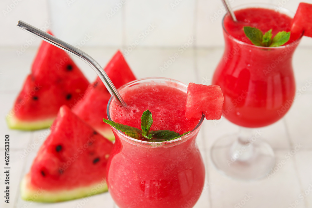 Glasses of tasty watermelon juice with mint on white tile background