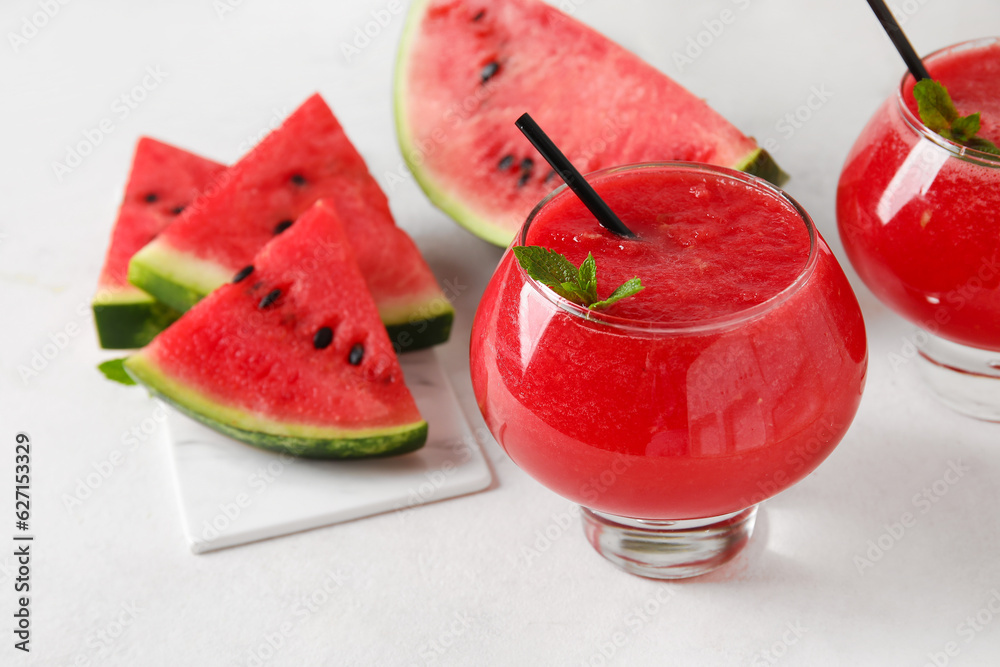 Glass of tasty watermelon juice with mint on white background