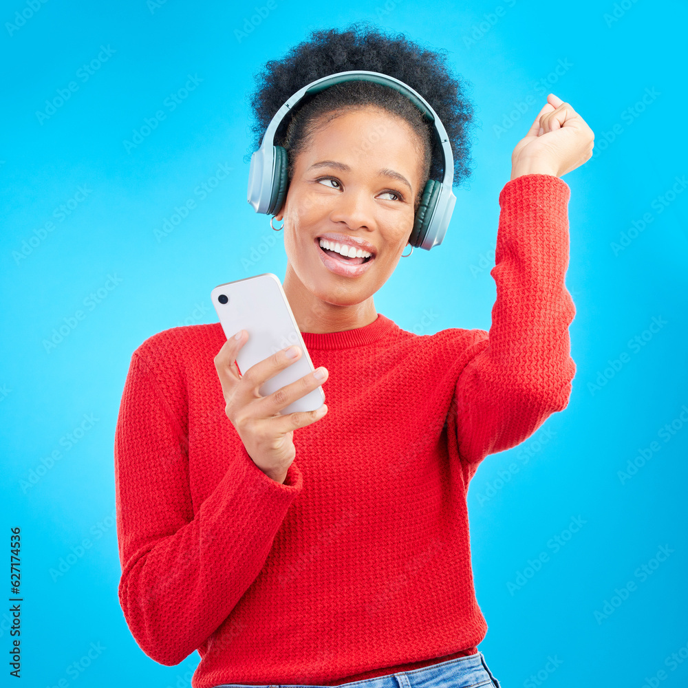 Happy woman, headphones and listening to music for audio streaming against a blue studio background.