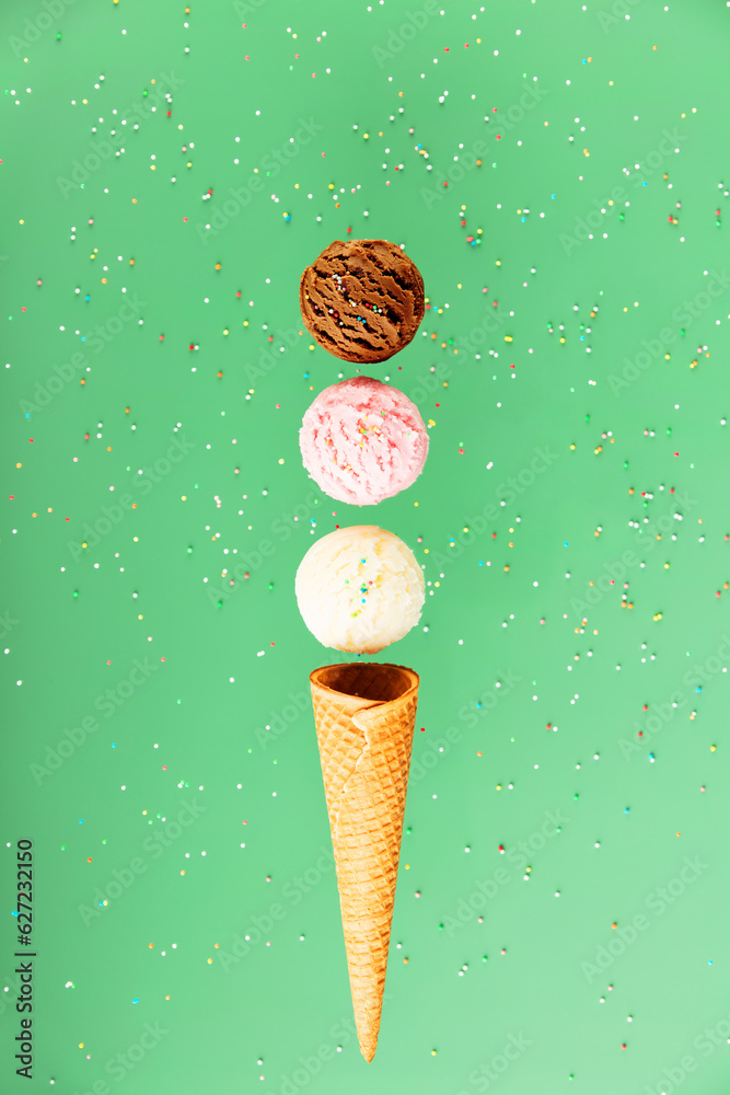 Chocolate, vanilla, strawberry scoops and waffle cone on green background with colorful sprinkles, l