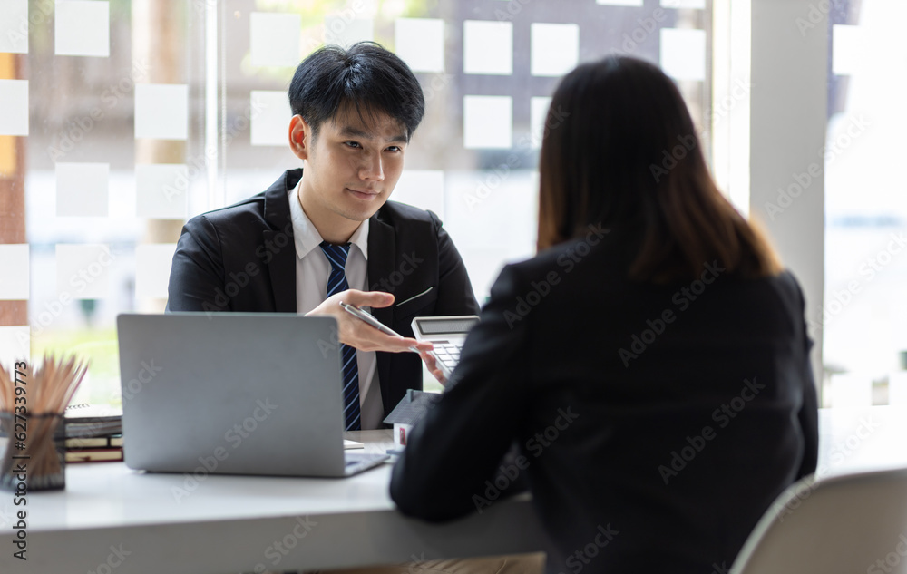 Businessman, real estate agent holding a calculator, presenting a price quote to a client for a hous