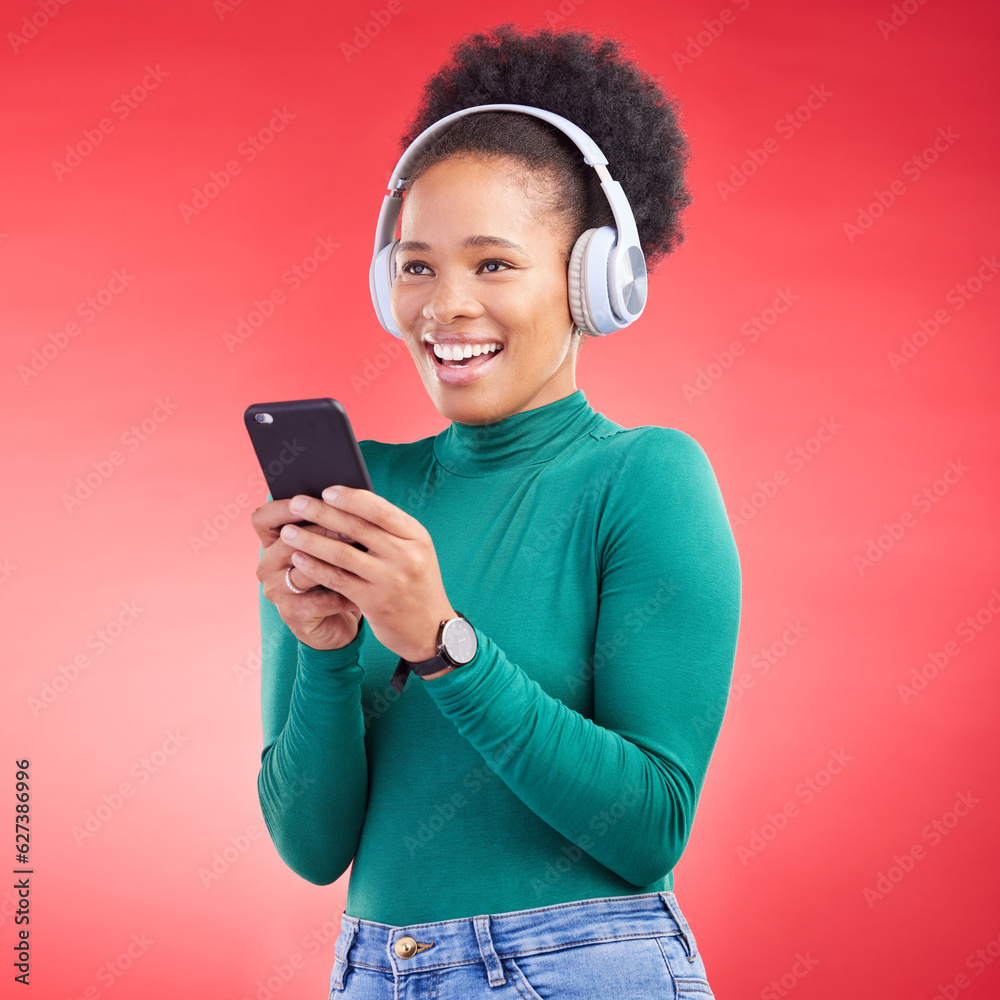 Happy woman, phone and listening to music on headphones against a red studio background. African fem