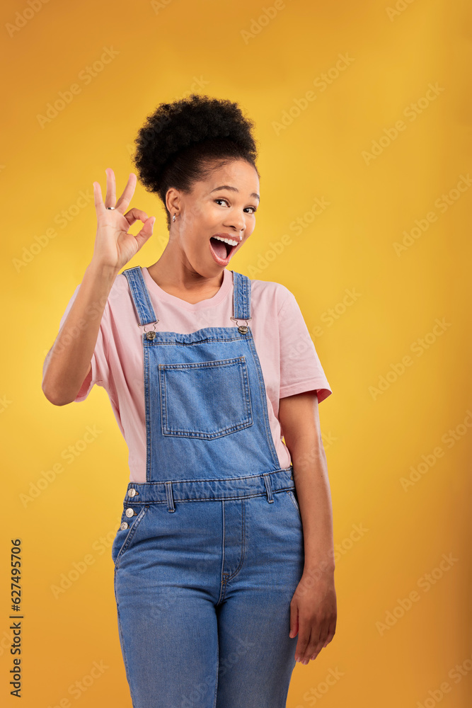 Portrait, okay and hand gesture with an excited black woman in studio on a yellow background. Smile,