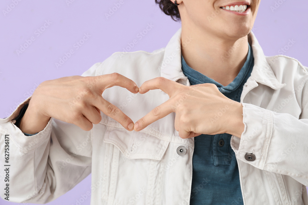 Young man making heart with his hands on lilac background, closeup