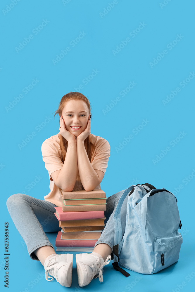 Female student with books sitting on blue background