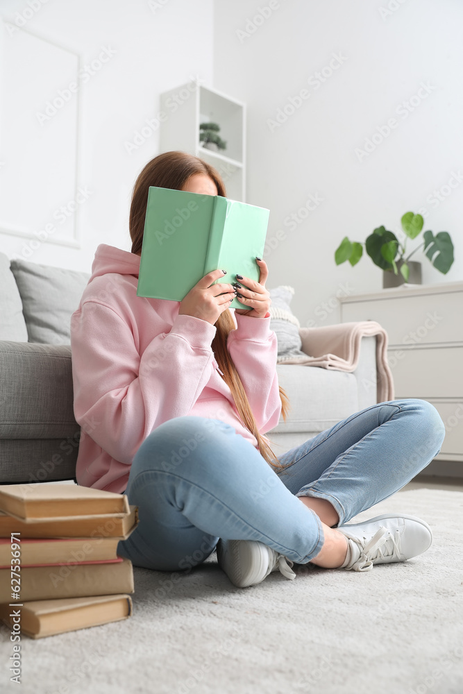 Teenage girl reading book at home