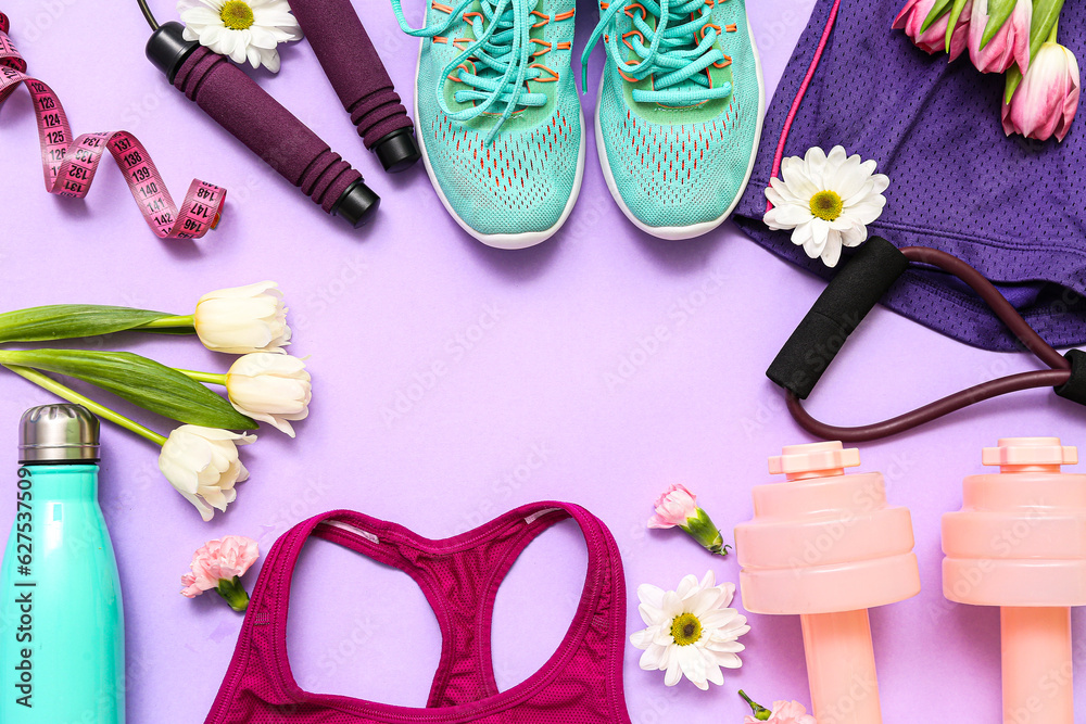 Frame made of sportswear with spring flowers and equipment on lilac background