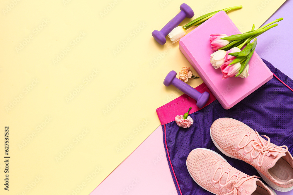 Sportswear with spring flowers and equipment on color background