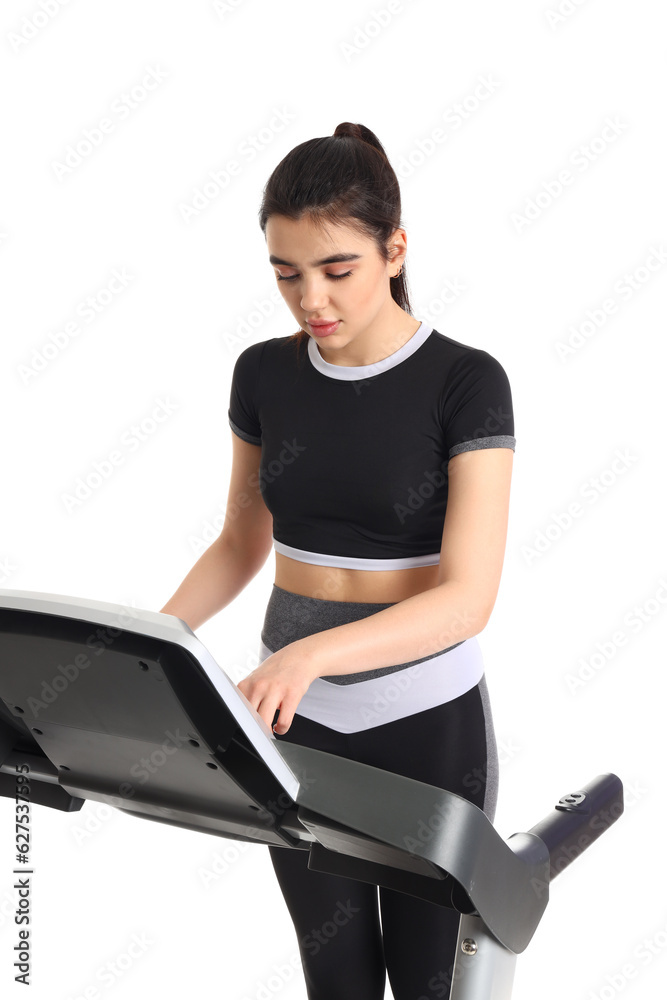 Sporty young woman training on treadmill against white background