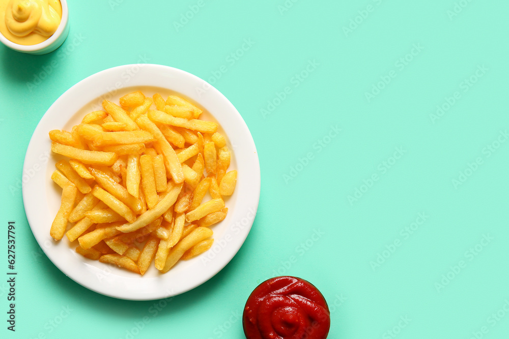 Plate of tasty french fries and sauces on color background