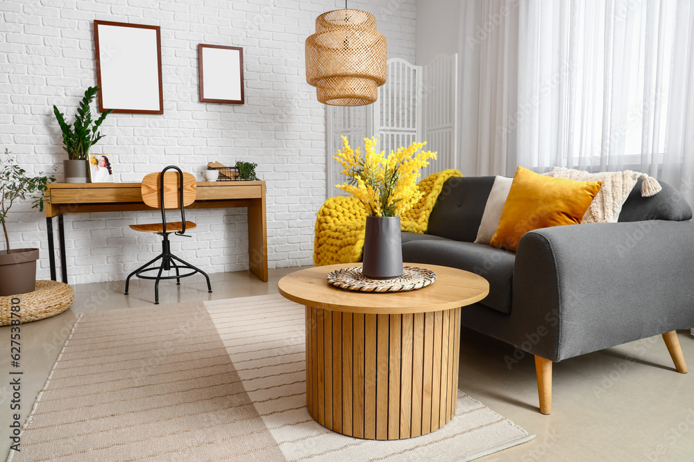 Interior of bright living room with coffee table, sofa and workplace