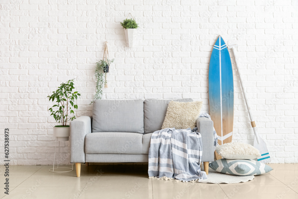 Interior of living room with surfboard, paddle and sofa