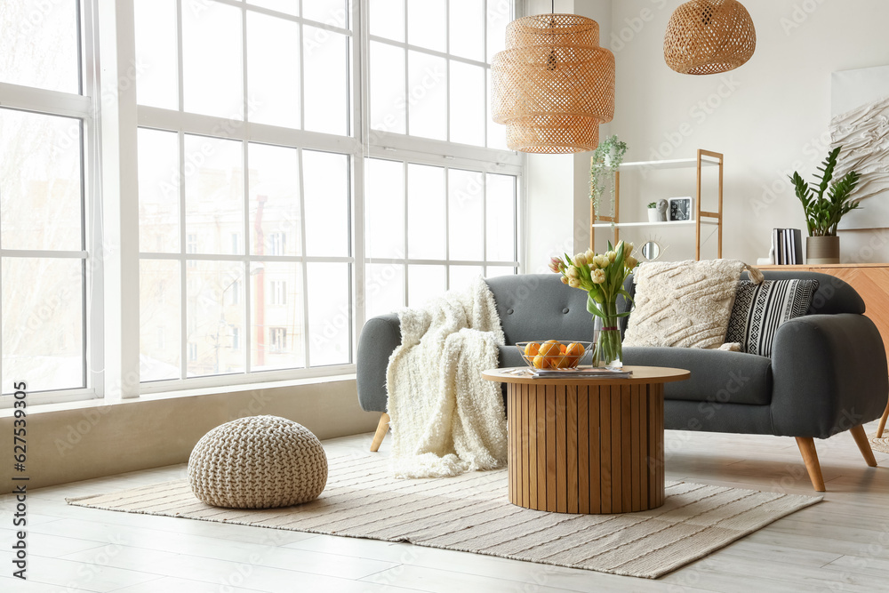 Interior of stylish living room with cozy sofa and coffee table near big window