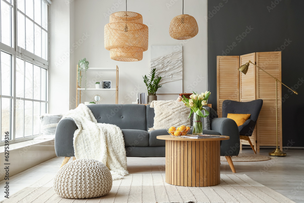 Interior of stylish living room with cozy sofa and coffee table near big window