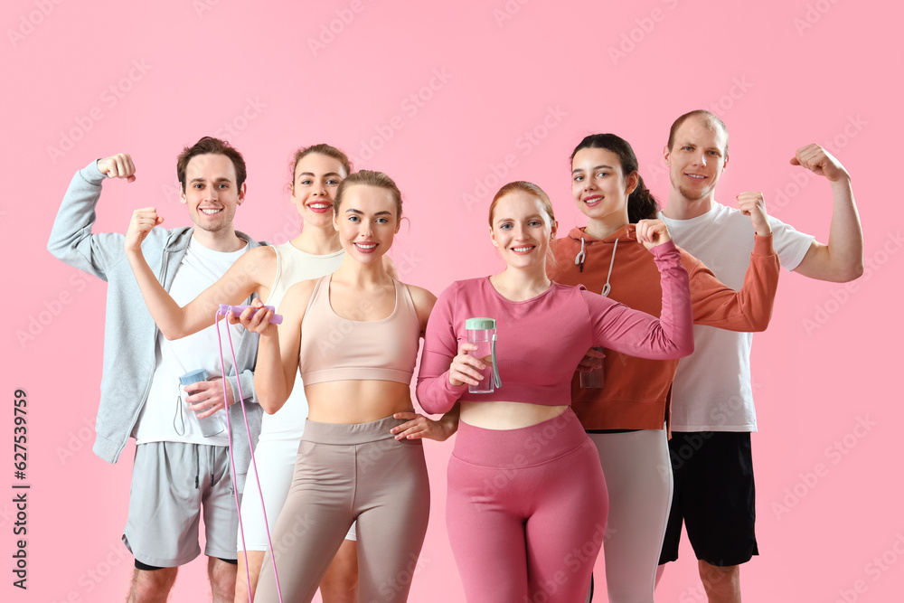 Group of sporty young people showing muscles on pink background