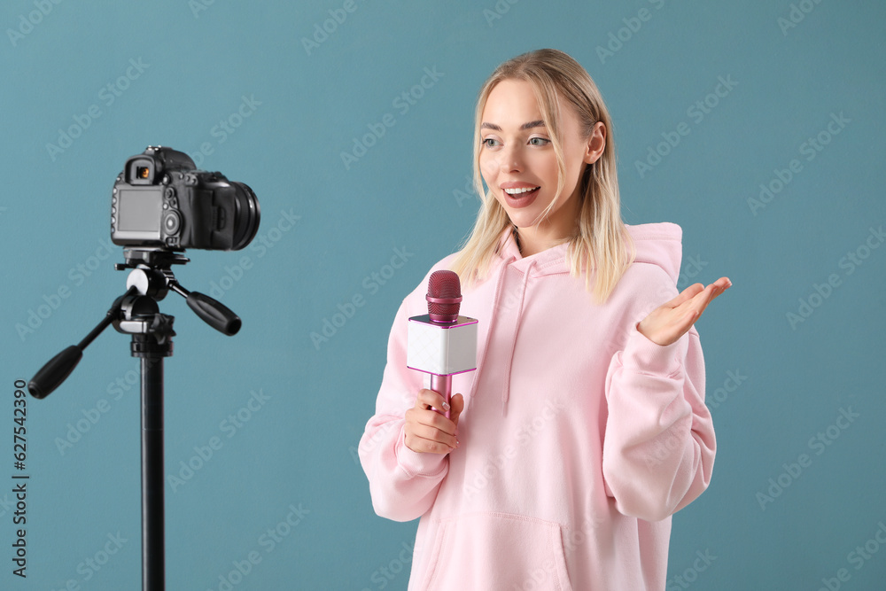 Female journalist with microphone recording video on blue background