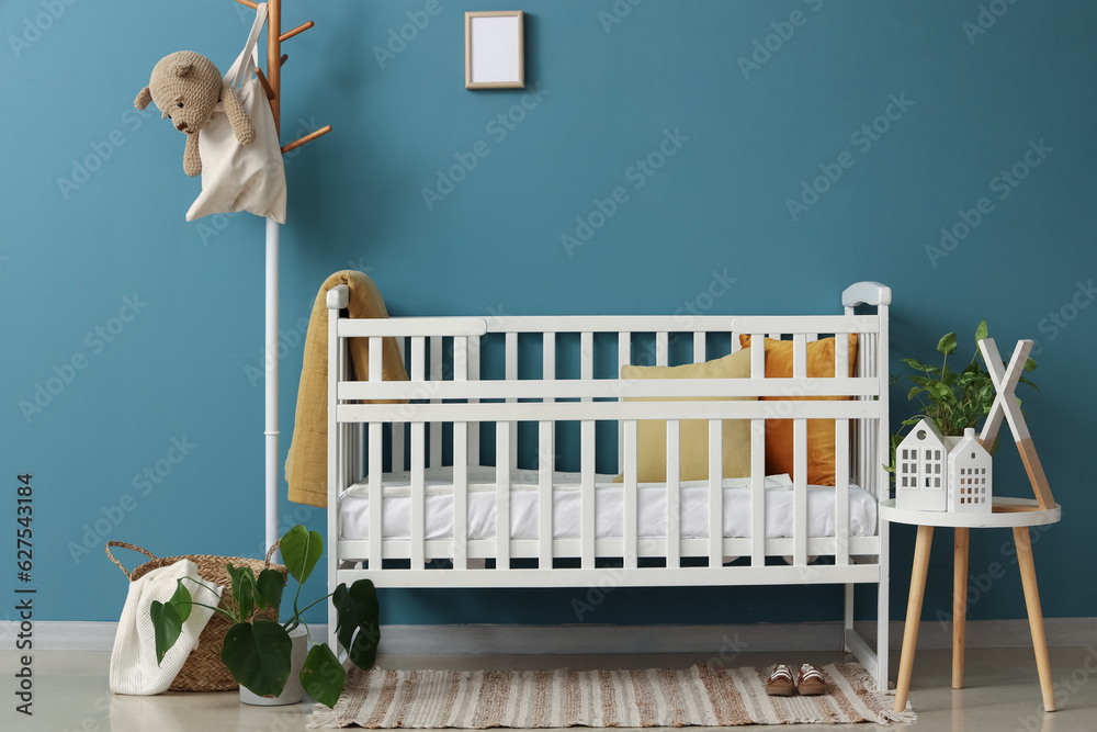 Interior of bedroom with baby crib, rack and table