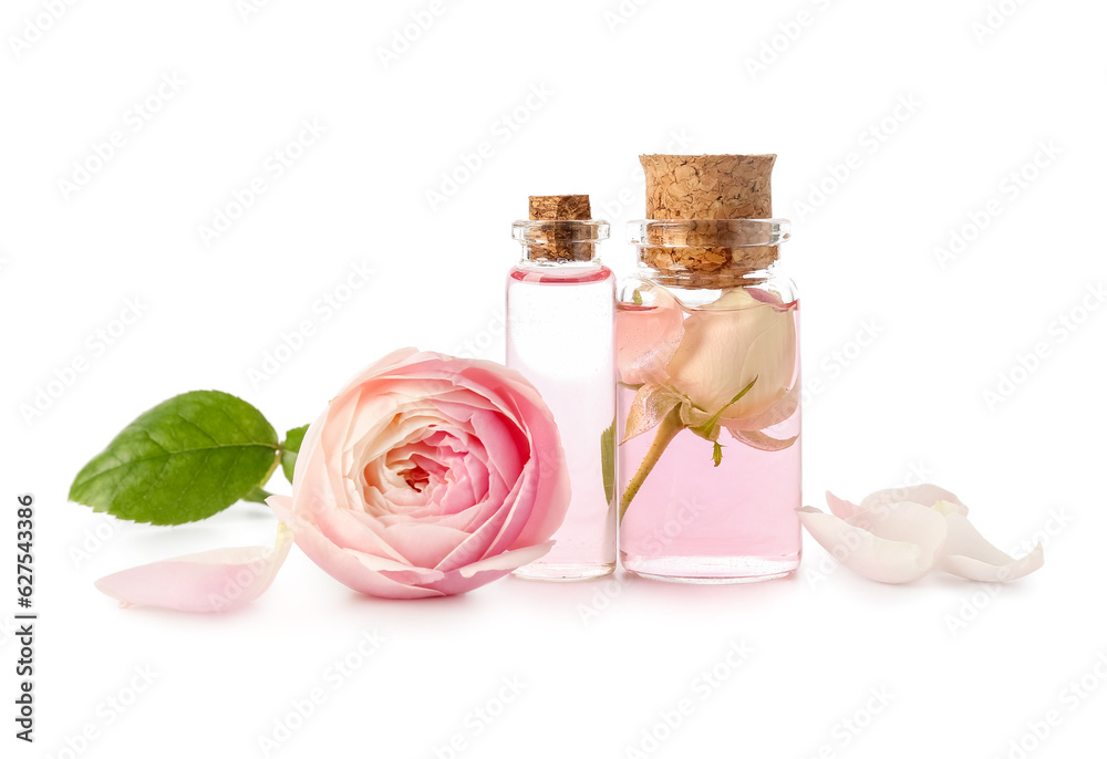 Bottles of cosmetic oil with rose extract and flower on white background