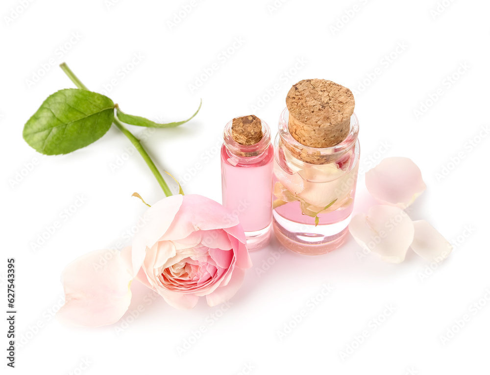 Bottles of cosmetic oil with rose extract and flower on white background