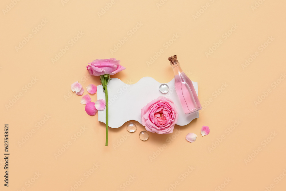 Bottle of cosmetic oil with rose extract and flowers on yellow background