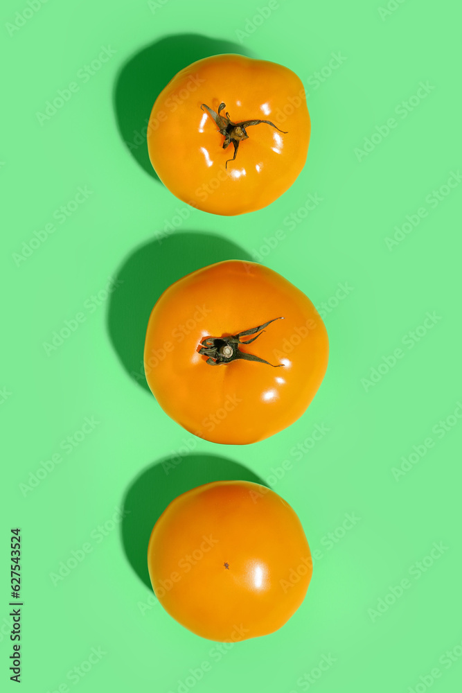 Fresh tomatoes on green background