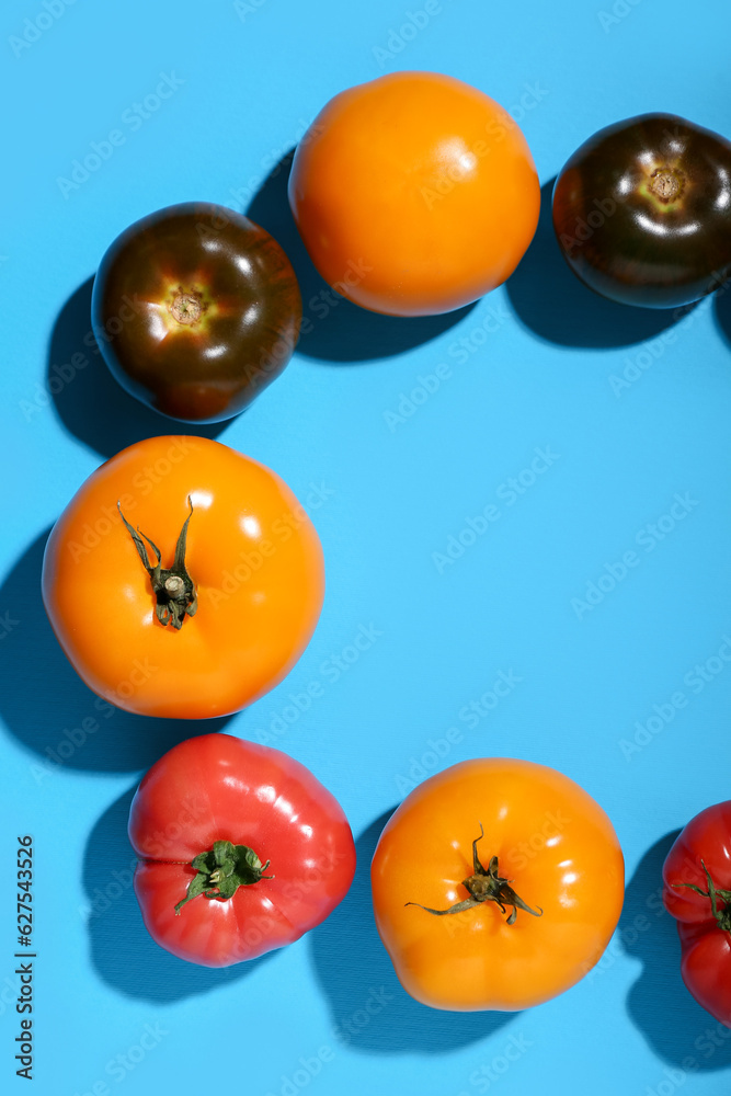 Frame made of different fresh tomatoes on blue background