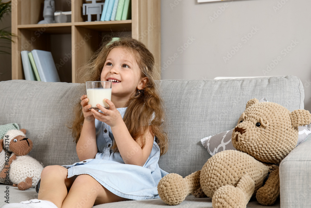 Cute little girl with glass of milk at home