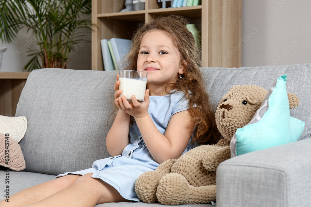 Cute little girl with glass of milk at home