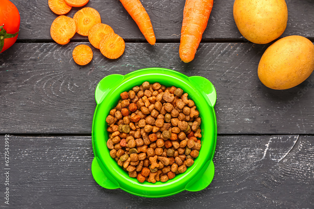 Bowl with dry pet food and natural products on dark wooden background