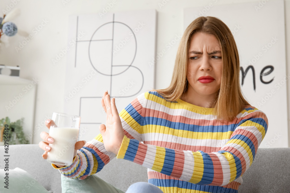 Displeased young woman with glass of milk at home