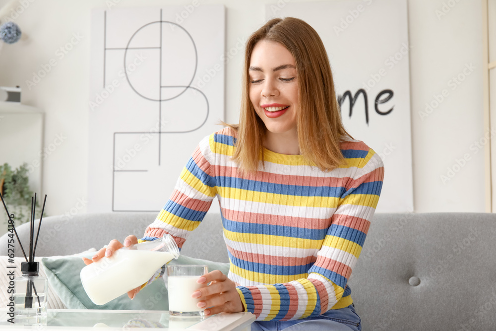 Young woman pouring milk into glass at home