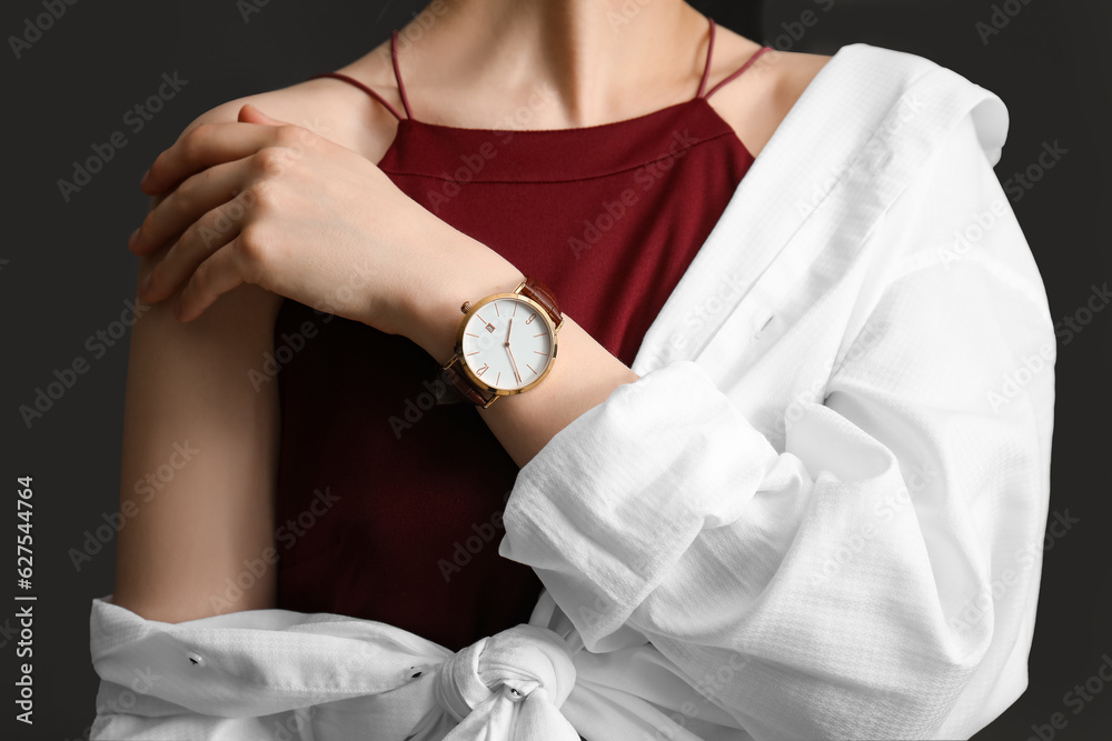 Elegant young woman with wristwatch on black background, closeup