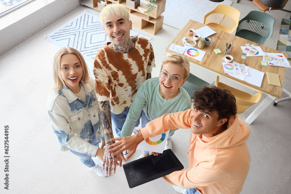 Team of graphic designers putting hands together in office