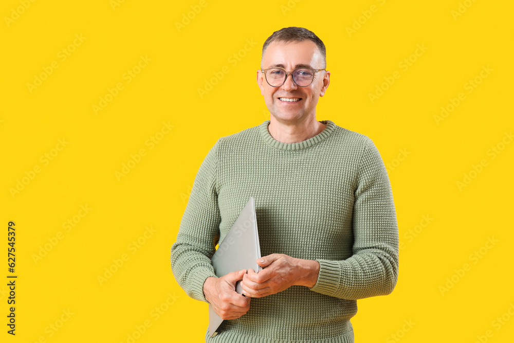 Mature male programmer with laptop on yellow background