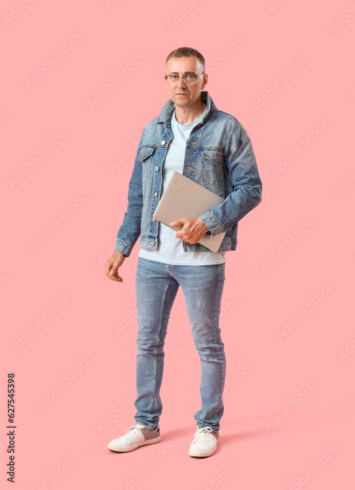 Mature male programmer with laptop on pink background