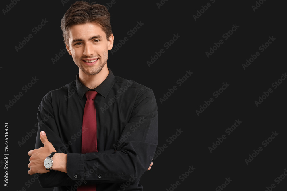 Handsome elegant young man with wristwatch on black background