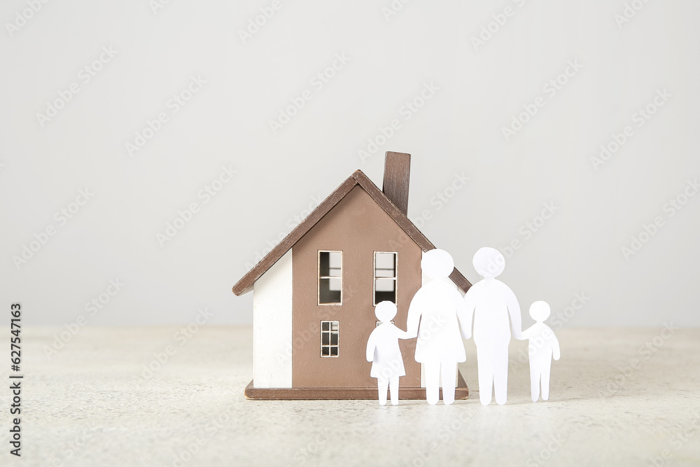 Figures of family with house on light background