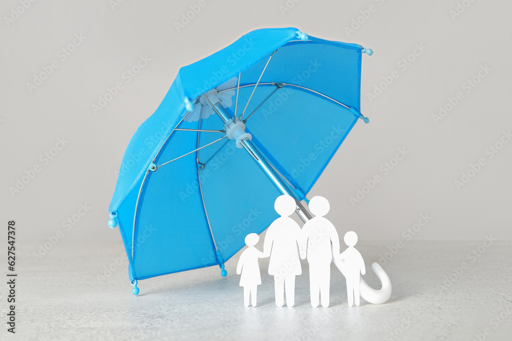 Figures of family with mini umbrella on white table. Insurance concept