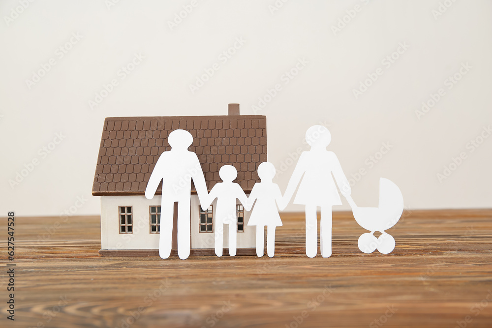 Figures of family with house on brown wooden table