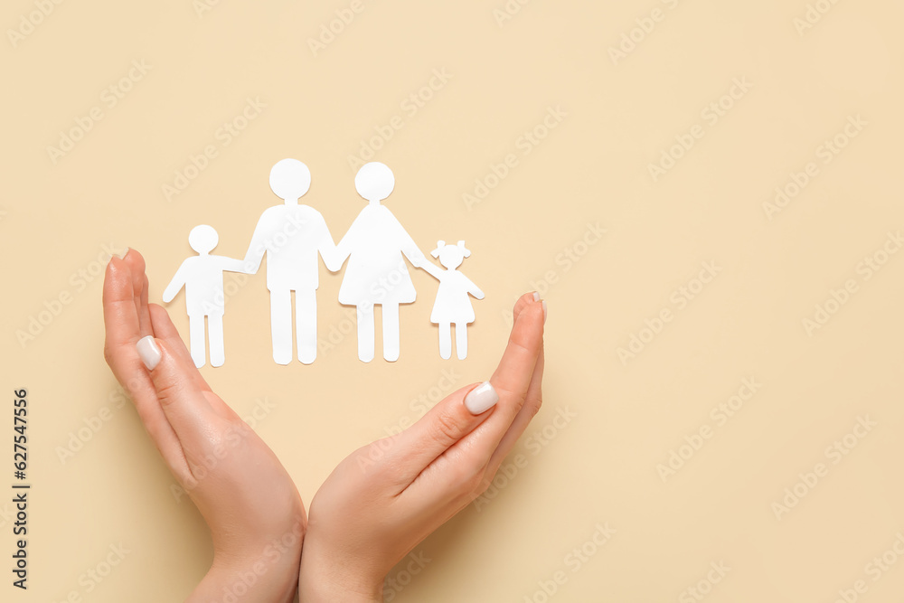 Female hands with figures of family on beige background. Insurance concept