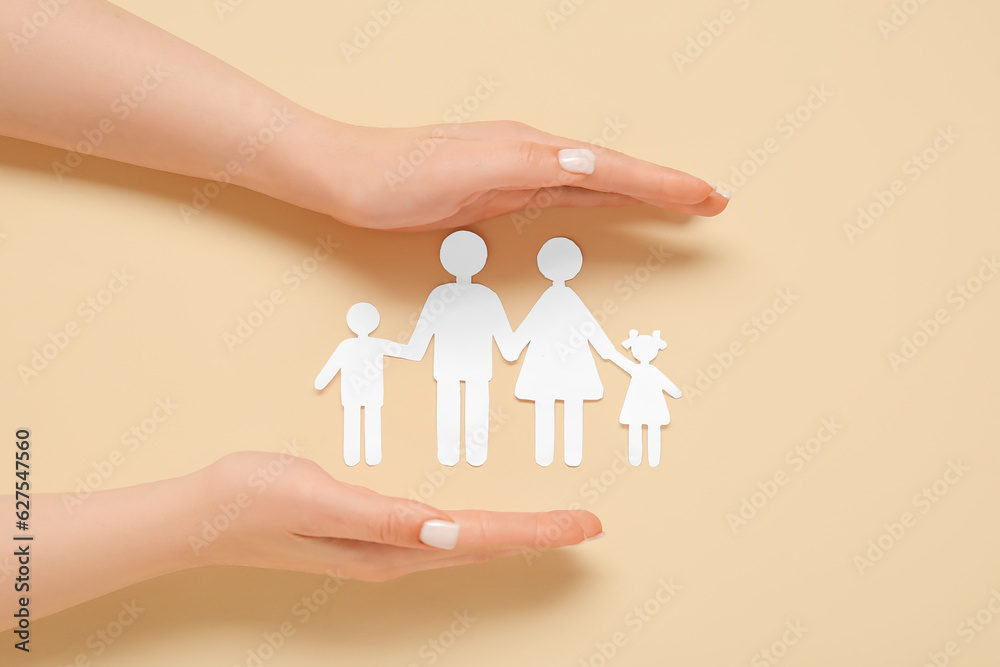 Female hands with figures of family on beige background. Insurance concept