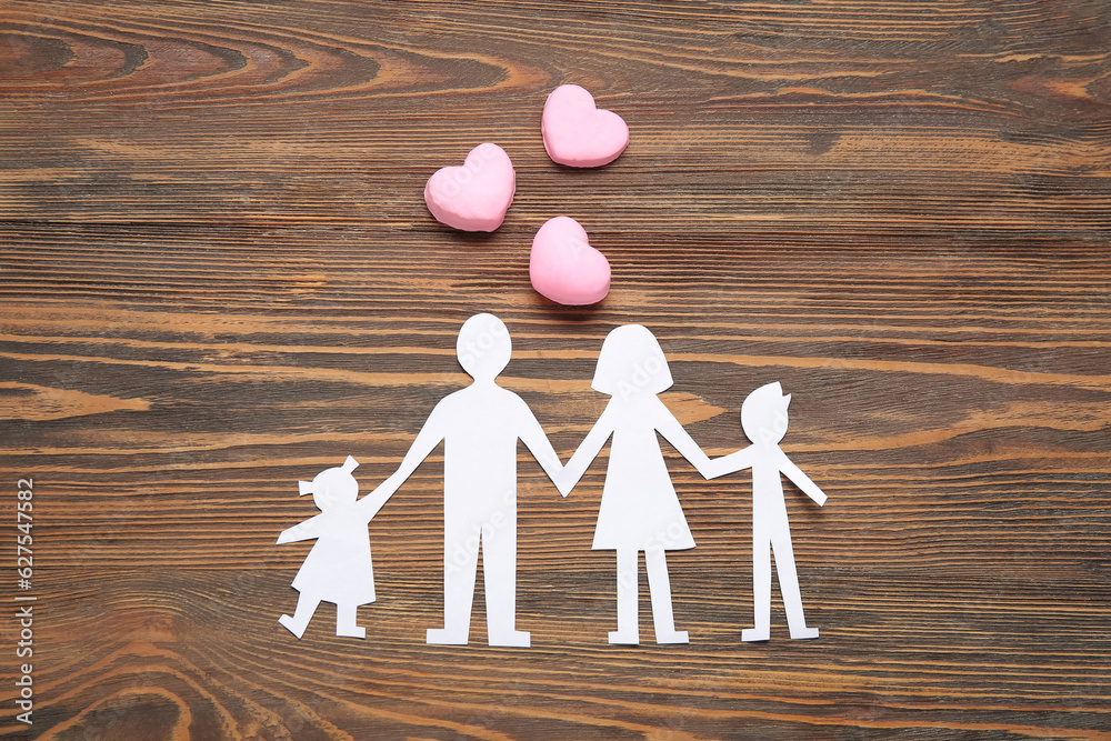 Figures of family and hearts on brown wooden background