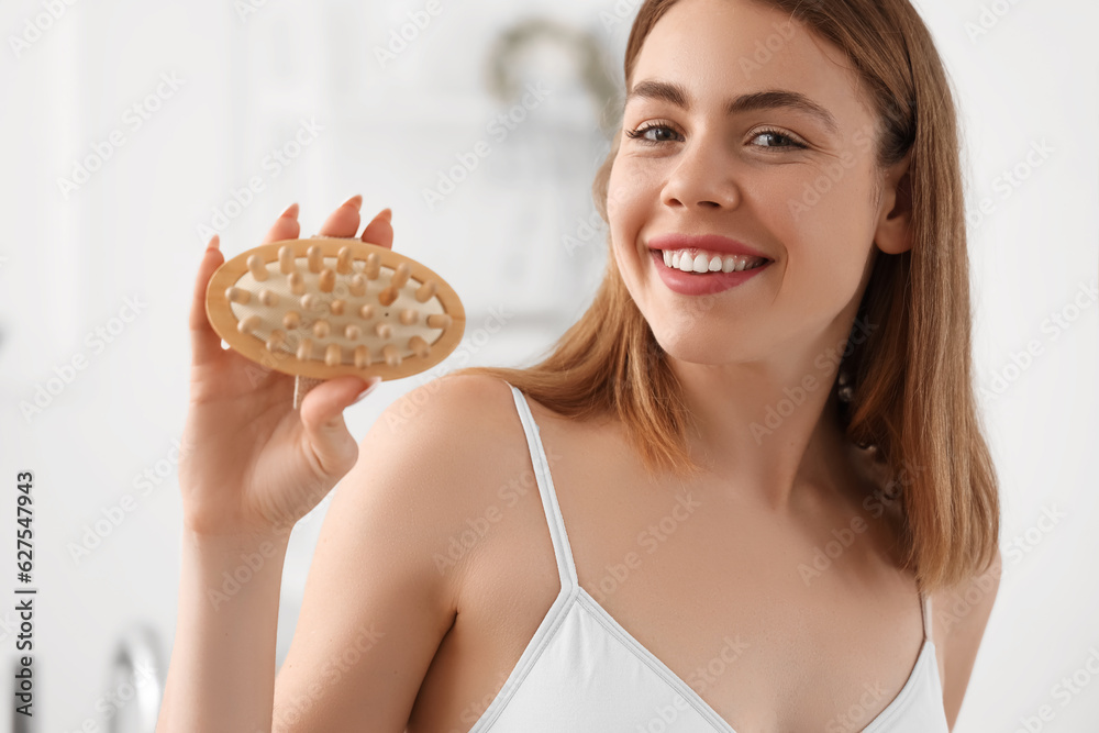 Young woman with anti-cellulite brush in bathroom, closeup