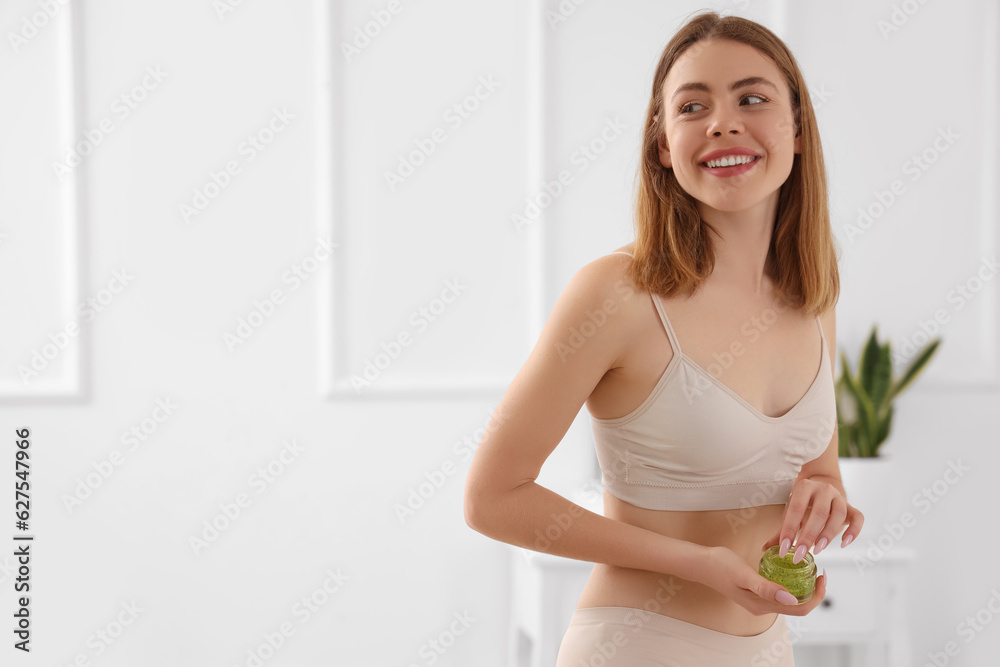 Young woman with anti-cellulite scrub in bathroom